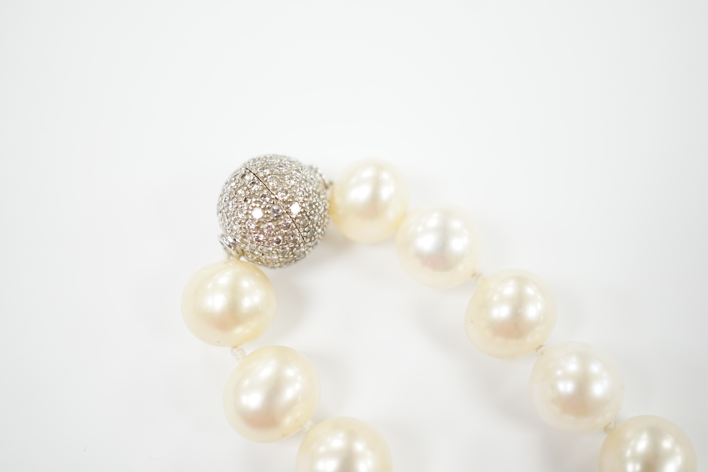 A modern single strand cultured pearl necklace with pave set diamond mounted spherical yellow metal clasp, 44cm.